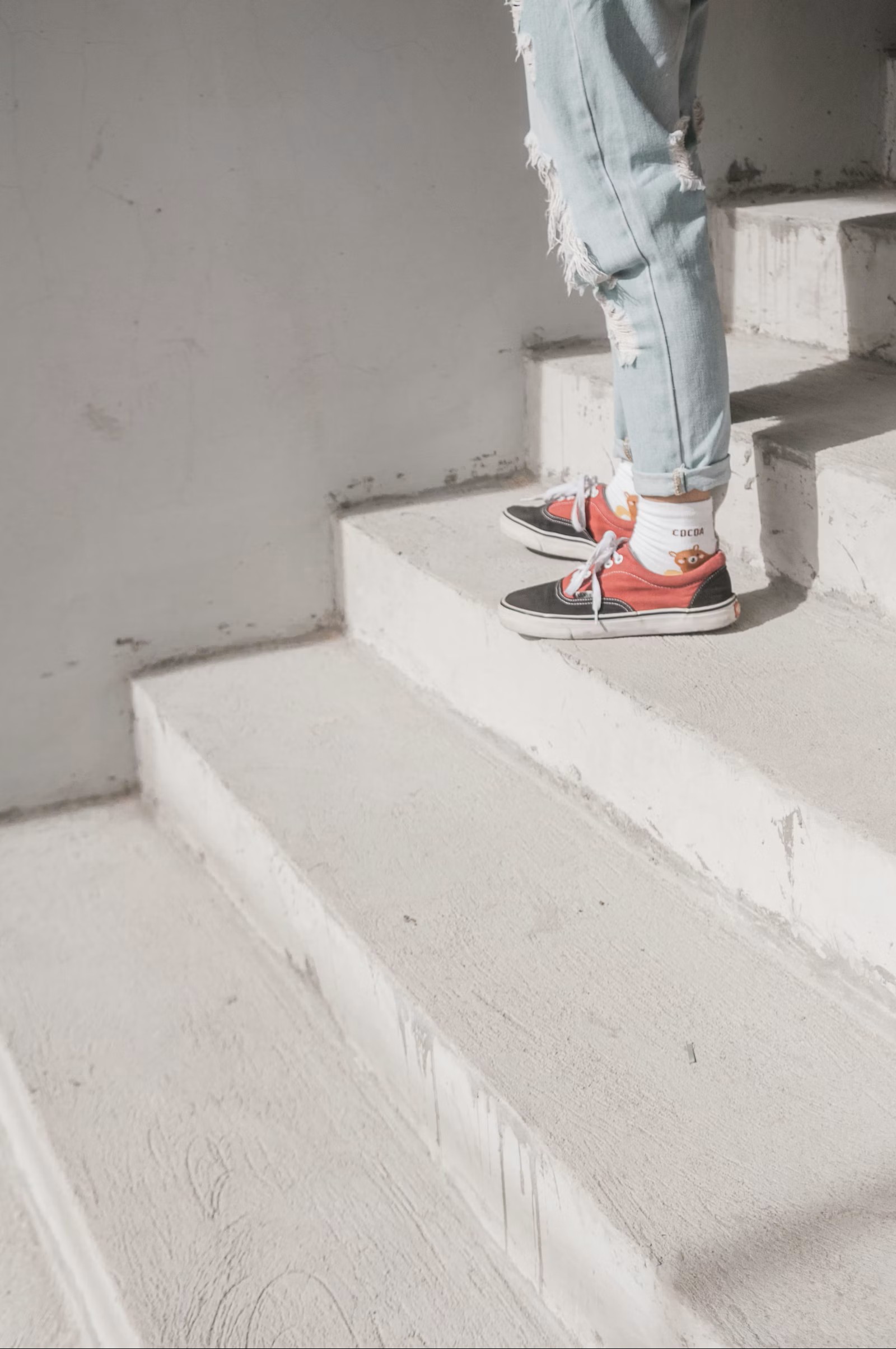 Person steht auf hellen Treppenstufen, Sneaker, stiller Moment